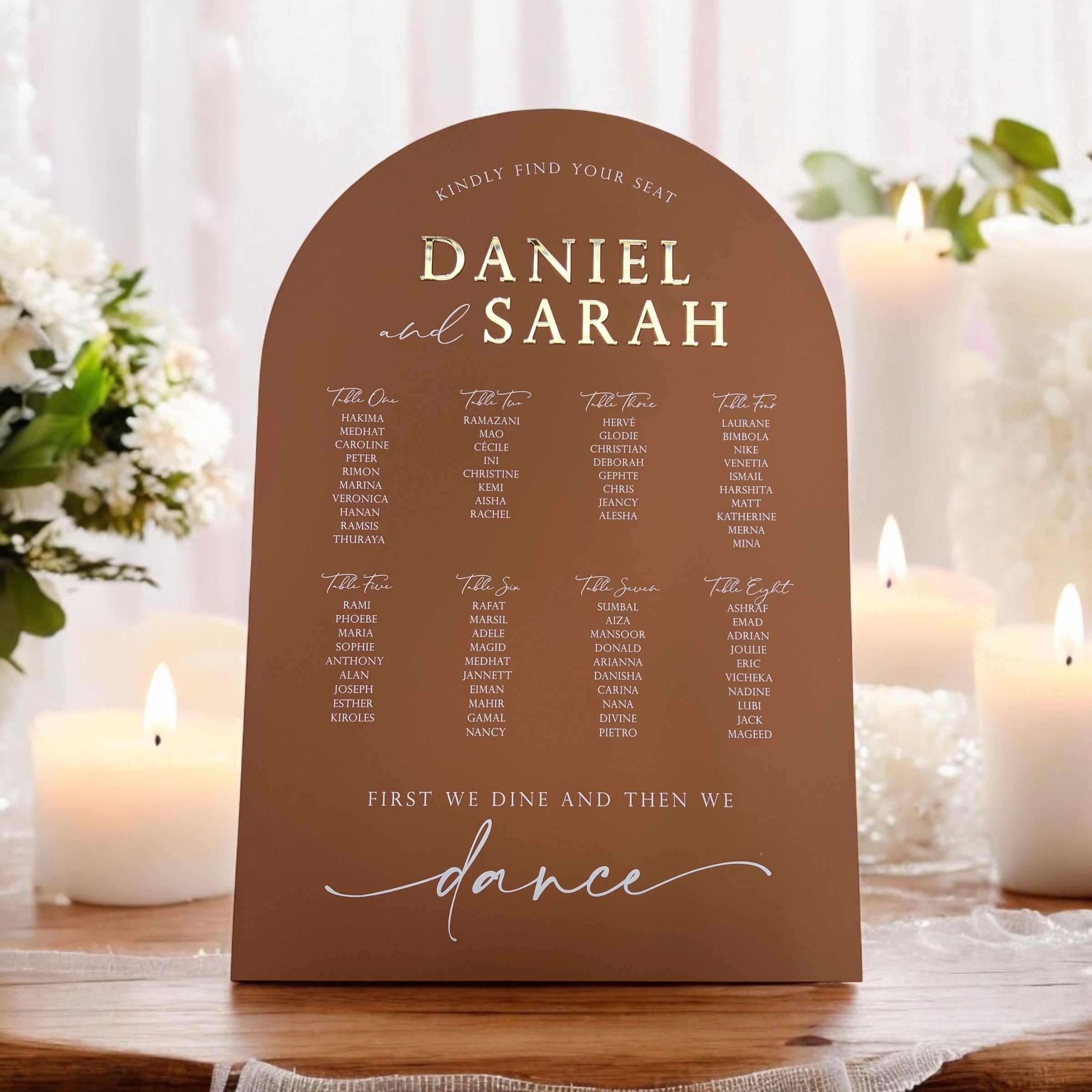 A collection of colorful name cards or place cards, each with a different color and text, placed on a white plate or napkin. The cards are arranged in a row, and there are flowers visible in the background.