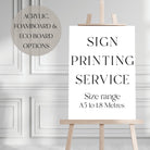 a white sign with black text that reads "ART WORK PRINTING SERVICE A1 A2 A3", placed on a wooden surface with additional Foamex and Acrylic options.