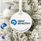 A white ornament with the text "cleardirection" and "Merry Christmas" hangs on a snow-covered pine tree.