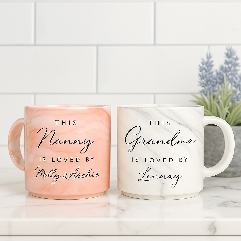 two coffee mugs with personalized messages, placed on a marble countertop.