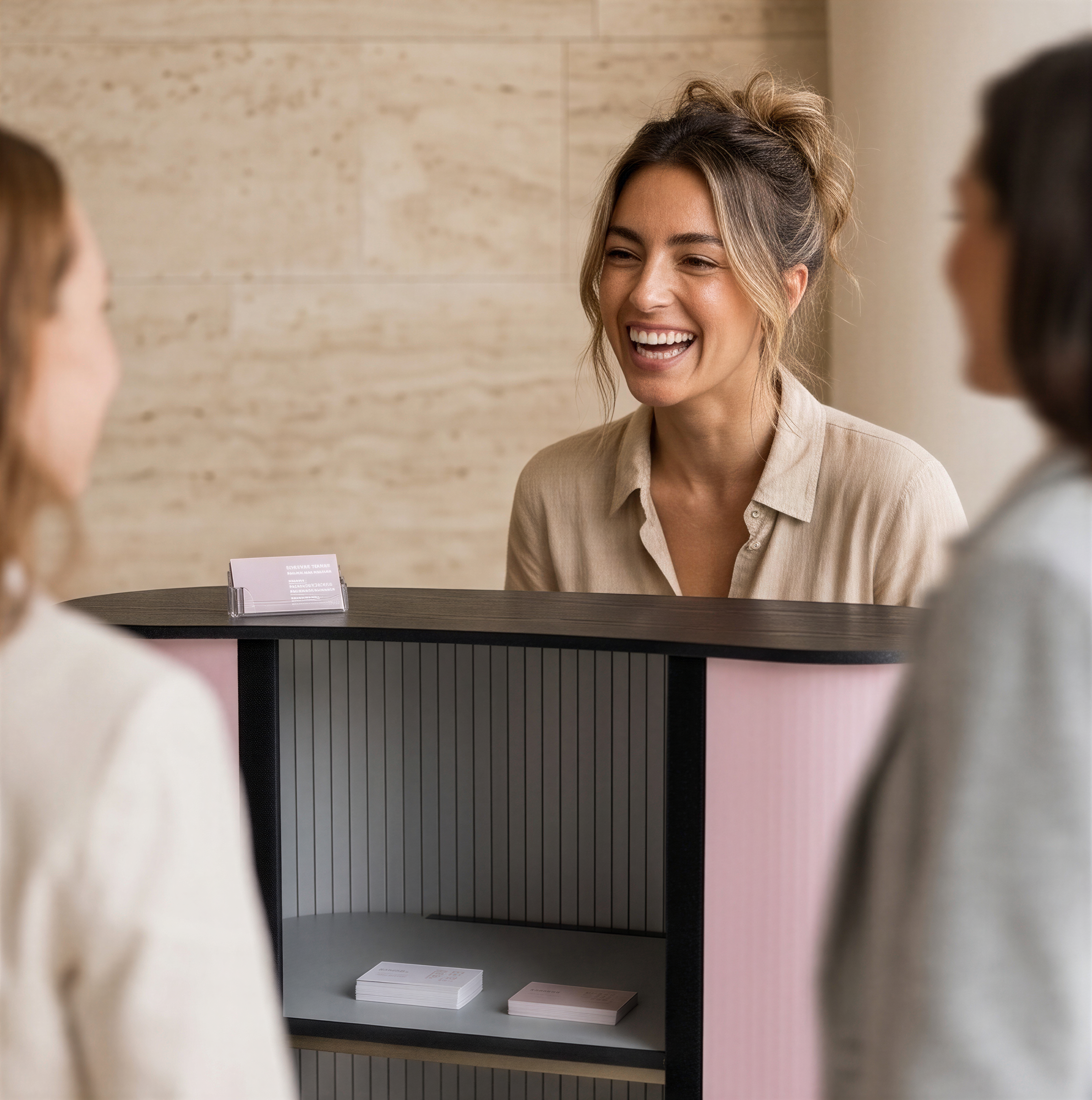 A woman is smiling and laughing while standing behind a counter, with two other people visible in the foreground.