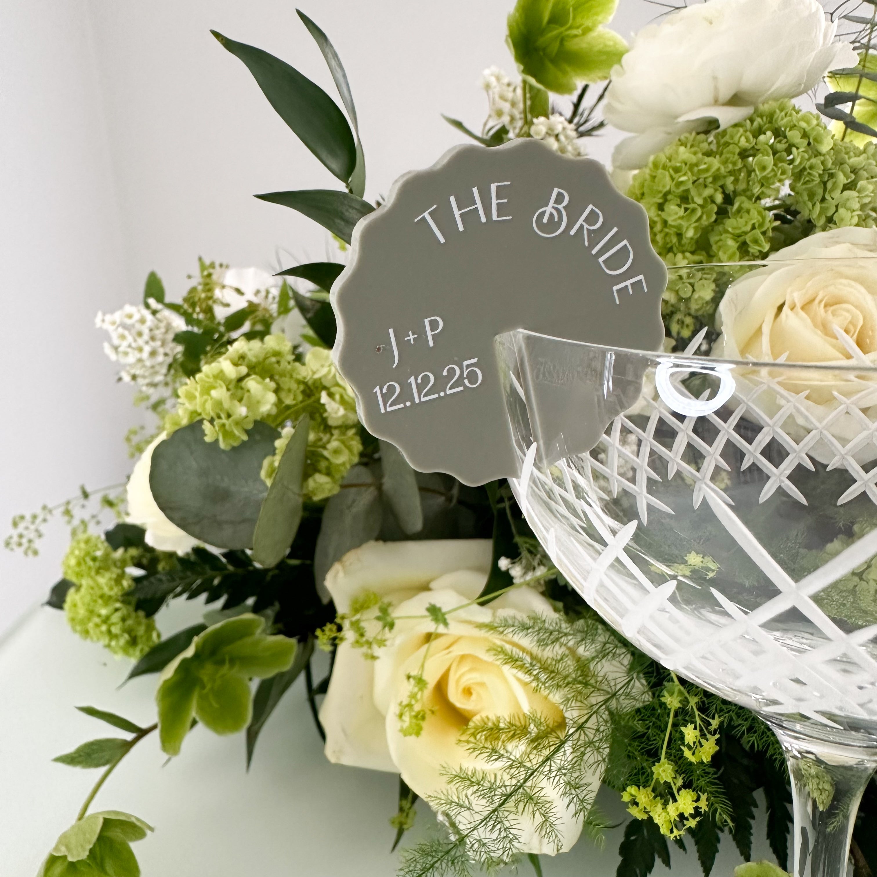 a white vase filled with white roses, with a sign attached to it that reads "THE BRIDE".