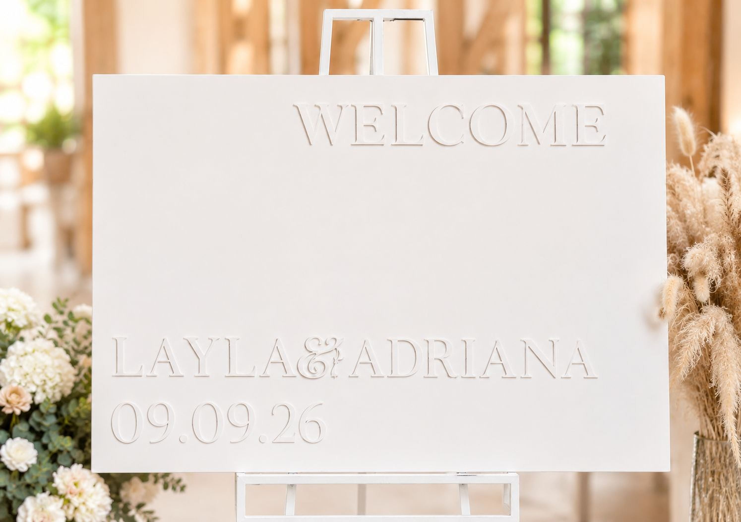 a white sign with the text "WELCOME LAYLA & ADRIANA 09.09.26" on it.