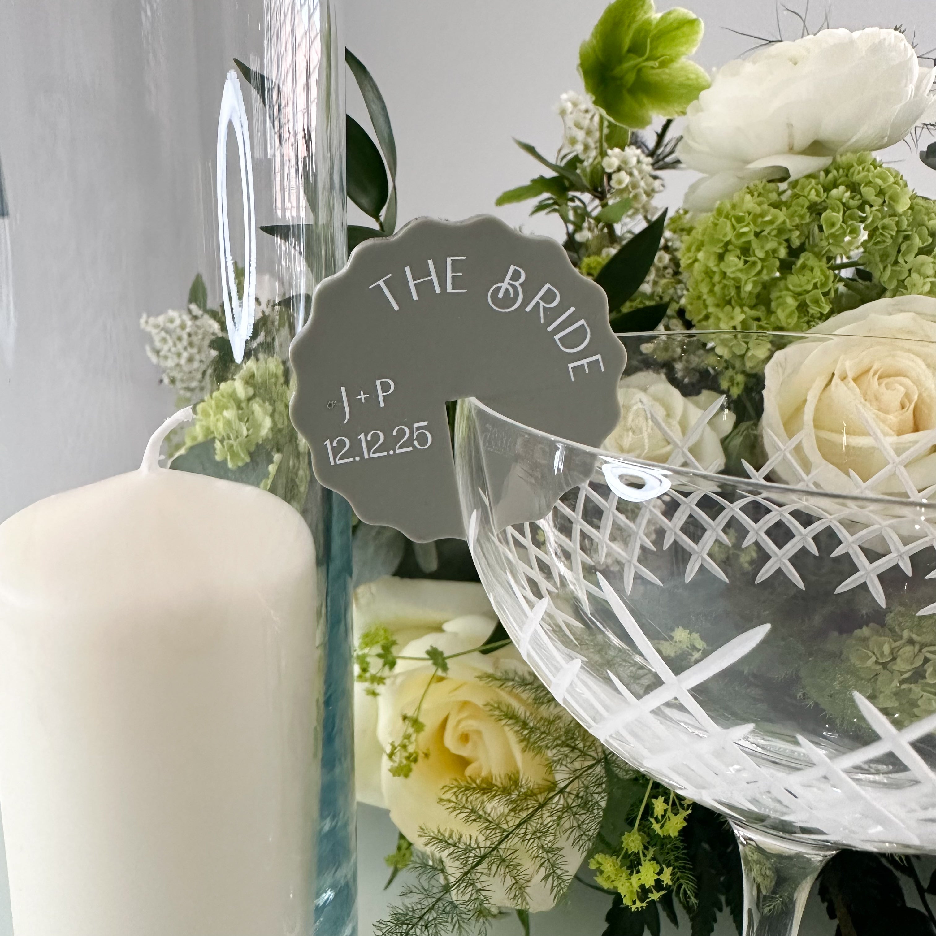 a pink flower-shaped tag with the personalised name "Hayley" written on it, surrounded by a colorful bouquet of pink and white flowers.