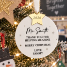a Christmas tree decorated with ornaments, including a personalized ornament that says "Mr. Smith" and "Thank you for helping me shine. Merry Christmas. Love Sammy". The tree is surrounded by other ornaments, and there is a chalkboard in the background.