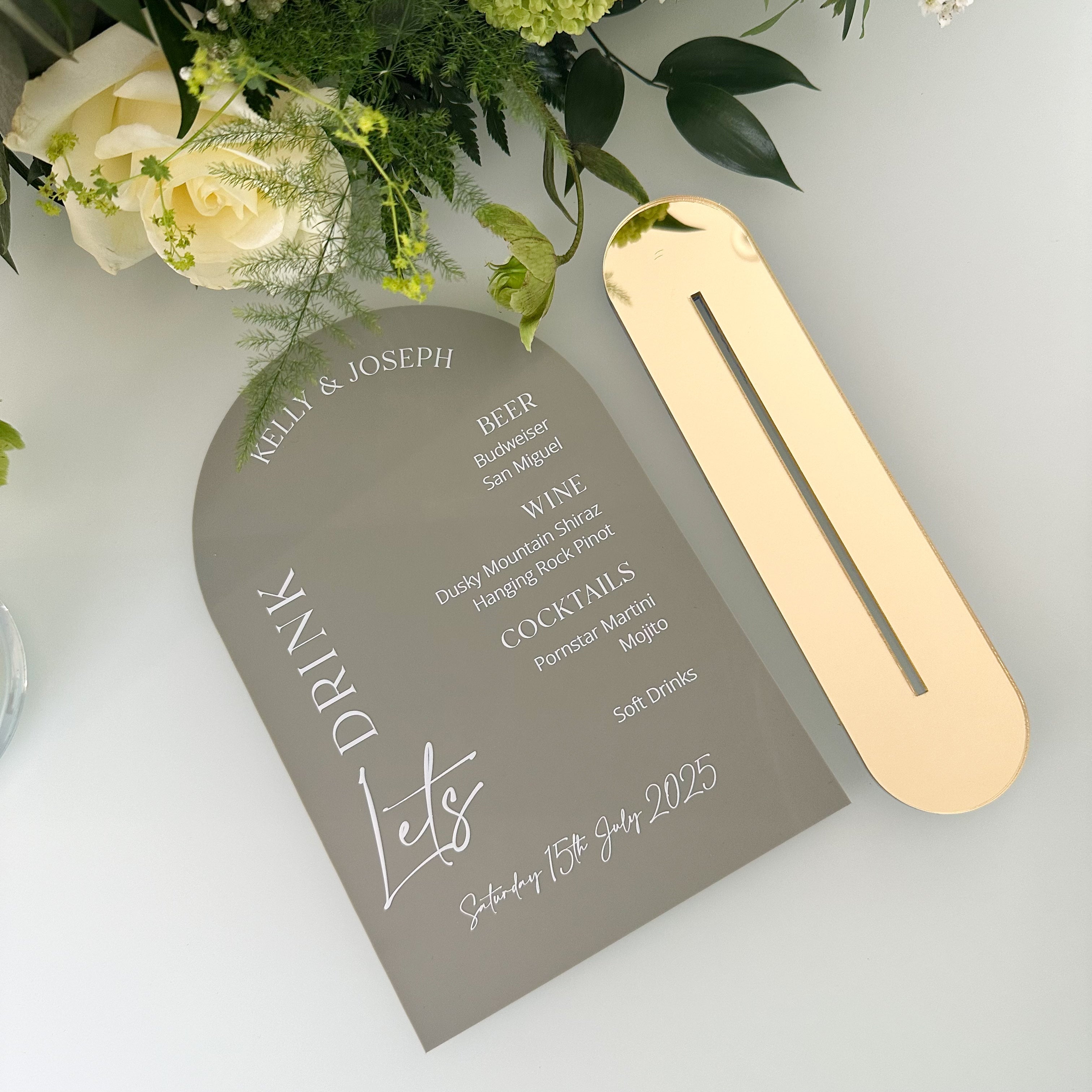 A collection of colorful name cards or place cards, each with a different color and text, placed on a white plate or napkin. The cards are arranged in a row, and there are flowers visible in the background.