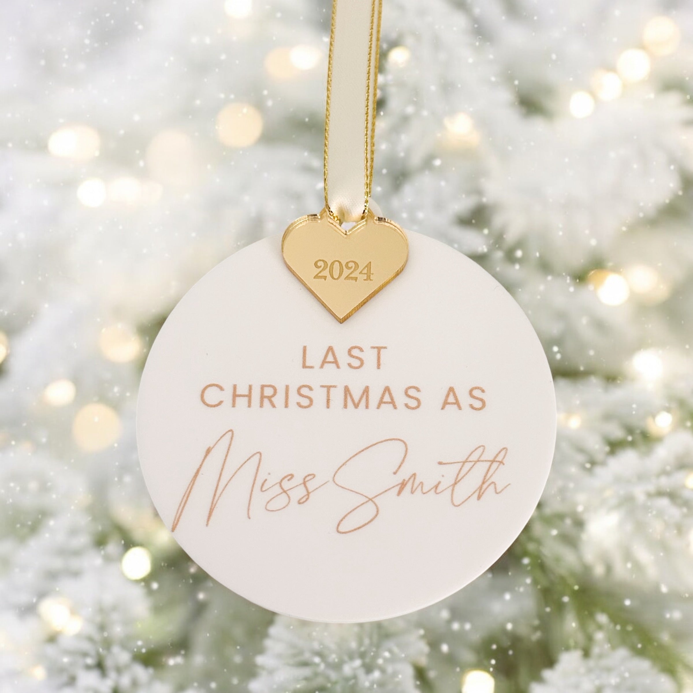 A black ornament with a silver ribbon and a heart-shaped ornament attached to it, hanging on a Christmas tree.