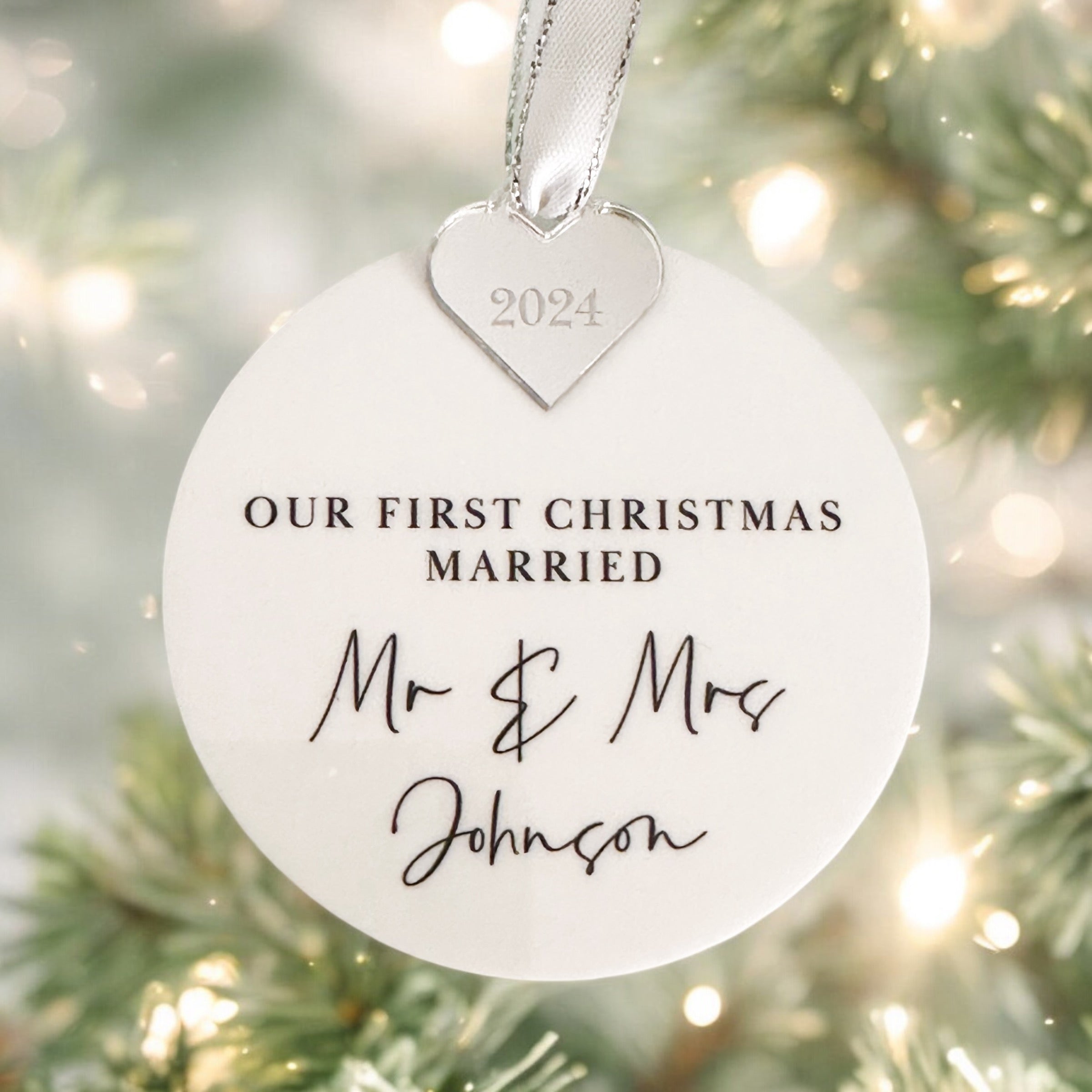 A gold heart-shaped ornament with a year engraved on it, hanging from a white ribbon.