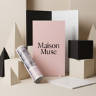 a pink poster with the text "Maison Muse" displayed prominently, surrounded by various geometric shapes and objects, including a rolled-up magazine or brochure.