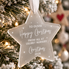 A clear star-shaped ornament with a message hanging on a Christmas tree.