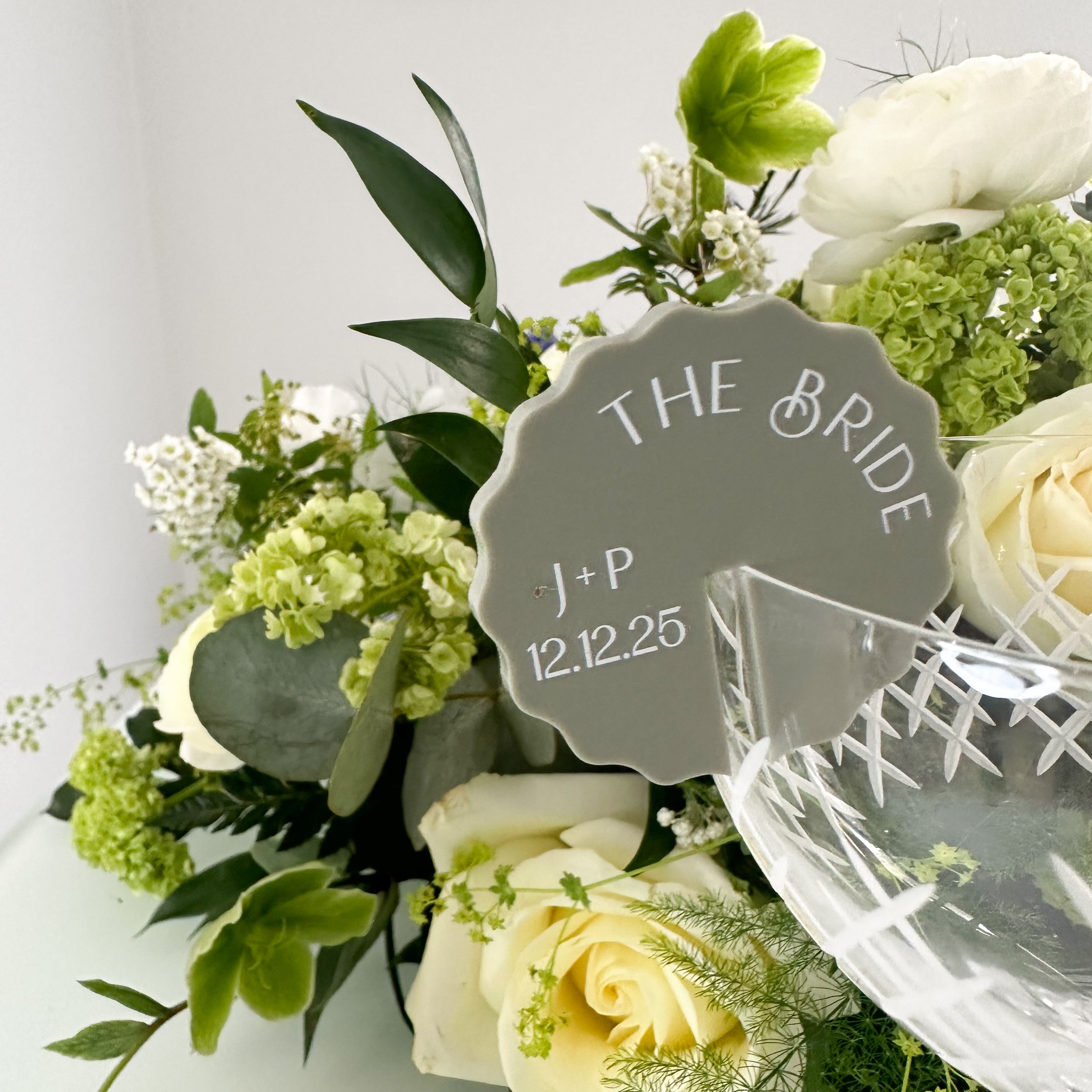 A collection of colorful name cards or place cards, each with a different color and text, placed on a white plate or napkin. The cards are arranged in a row, and there are flowers visible in the background.