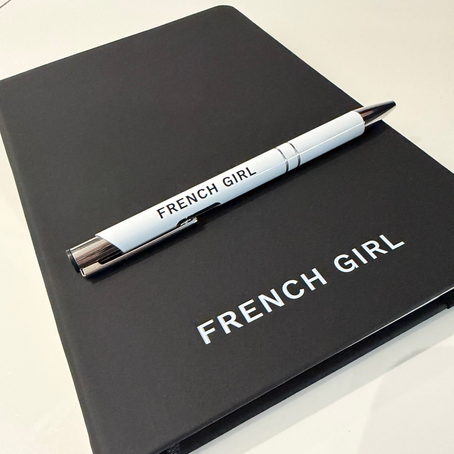 Black notebook branding and a matching pen on a white background