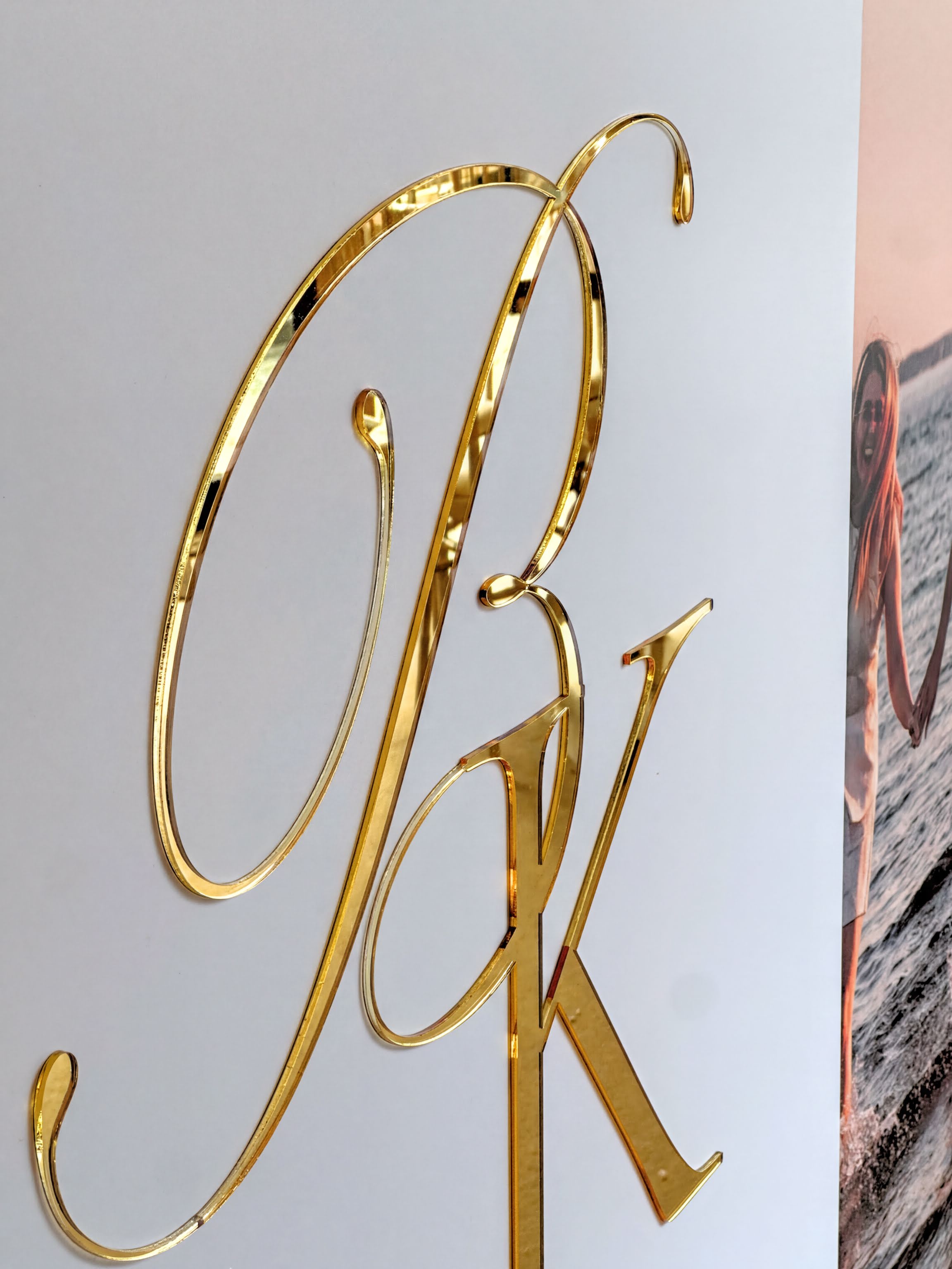 a close-up view of a golden letter "P" and "K" on a white background.