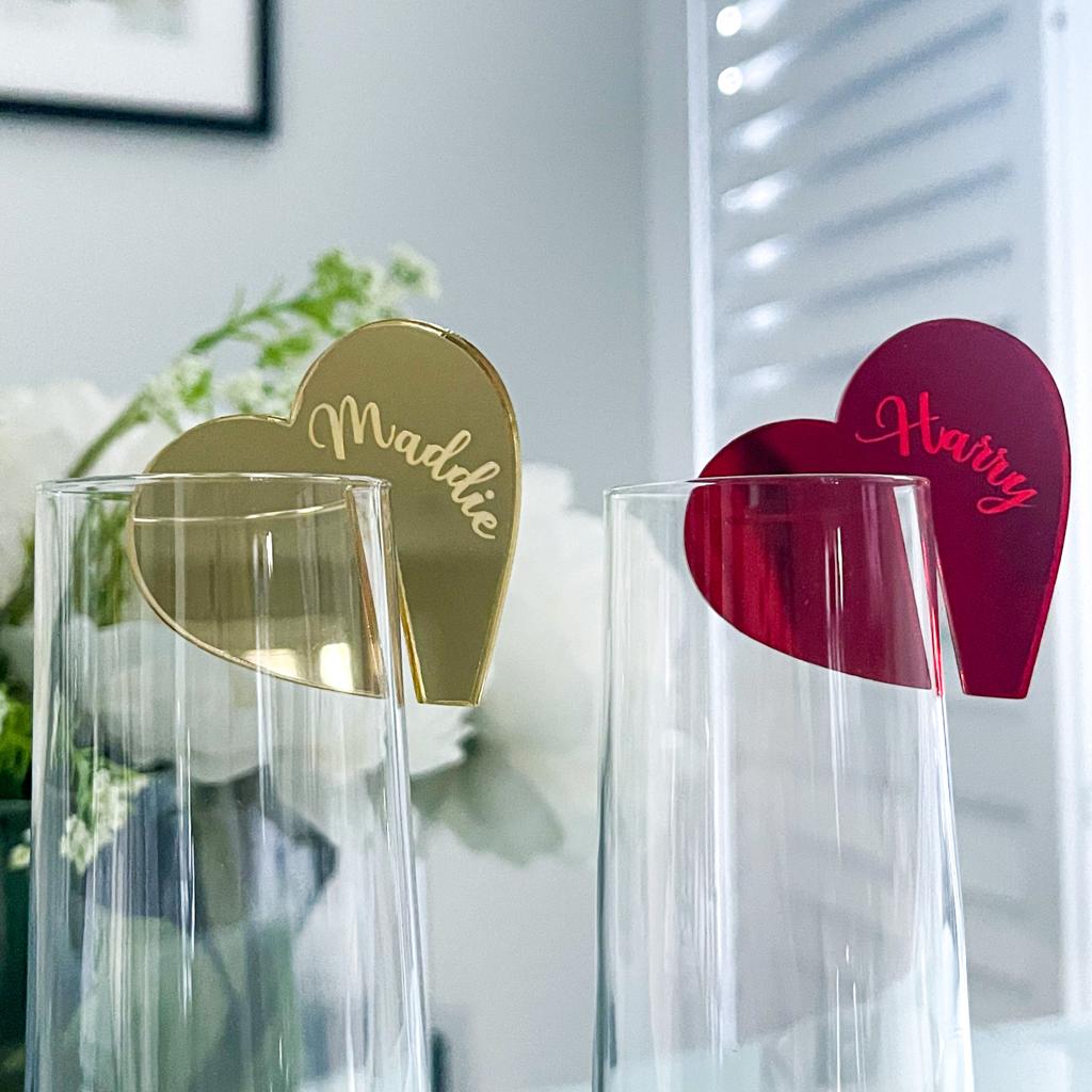 Two heart-shaped cutouts, one gold and one red, with personalized names engraved on them.