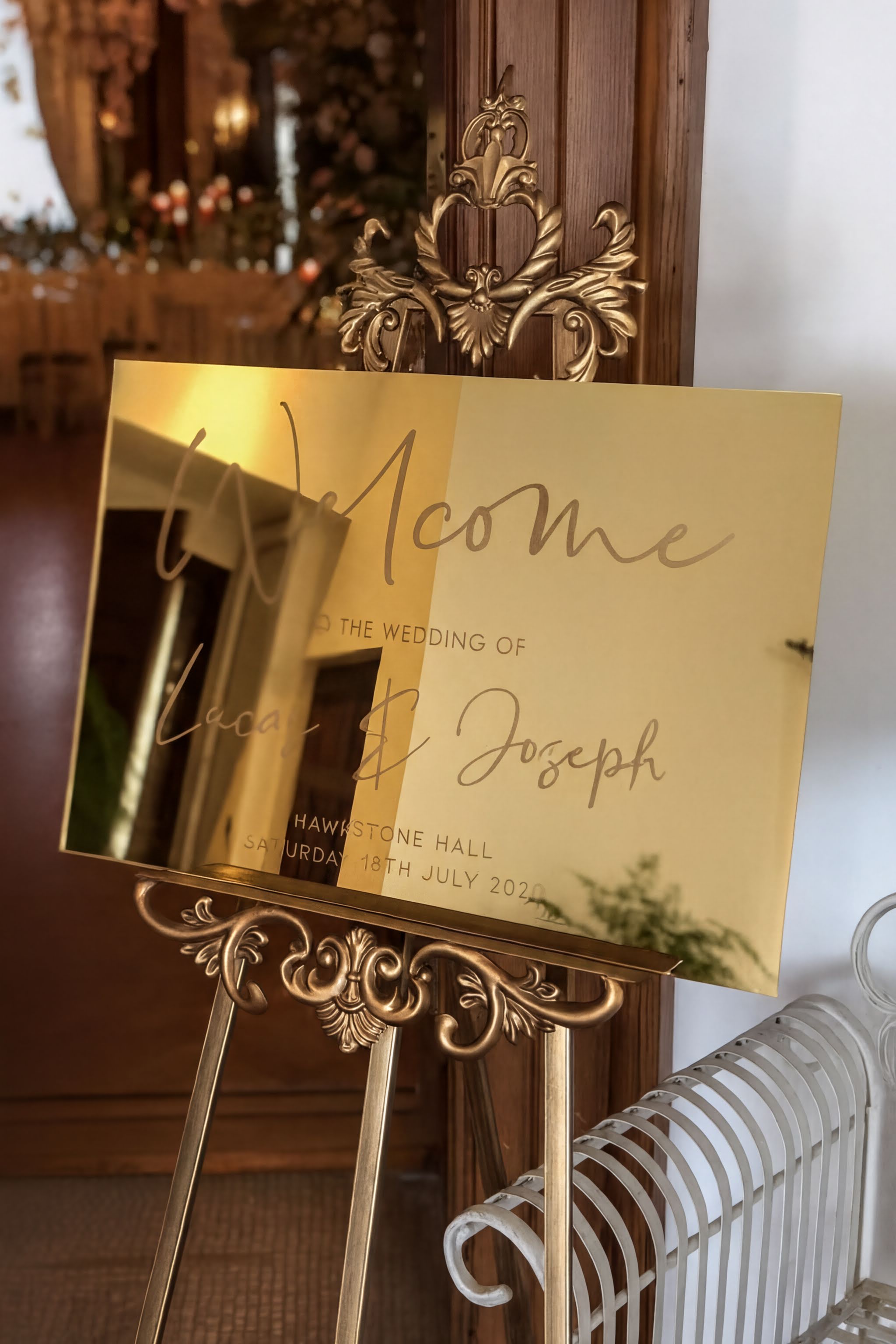 a golden wedding welcome sign with the names "Lena & Joseph" and the date "Saturday, July 18th, 2020" displayed on it.