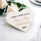 A heart-shaped object with personalised text on it, placed on a pink background.