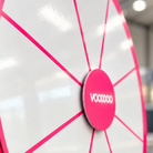 A close-up of a large, bright pink spinning wheel with the word "VOOVO" written on it.