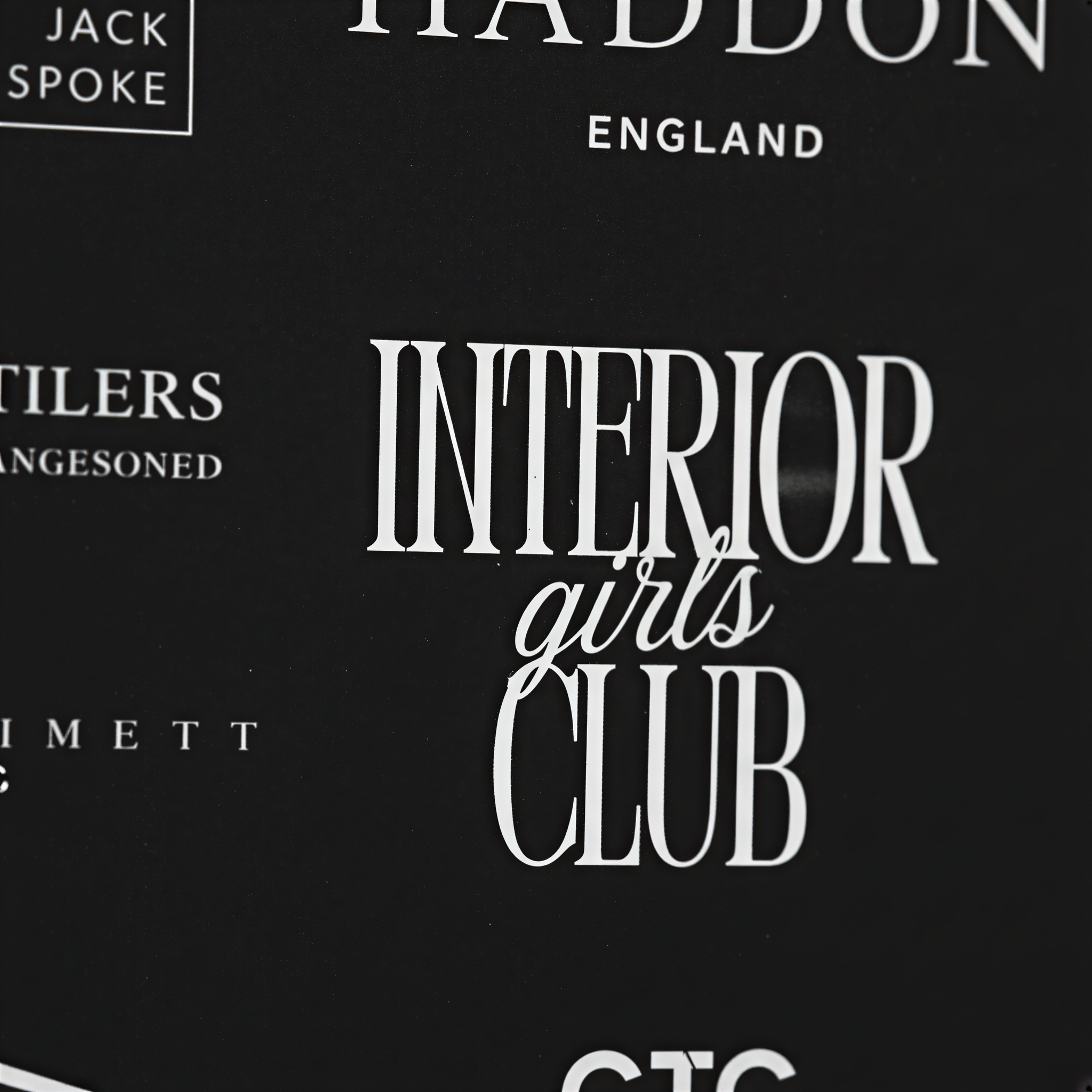 a close-up view of a black background with white text and logos. The text and logos appear to be related to a club or organization, but the exact content is not clear due to the close-up nature of the image.