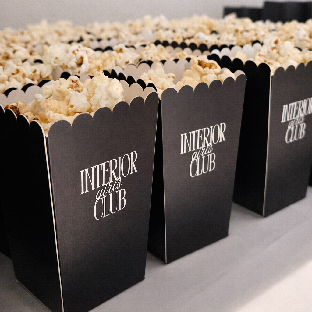 a row of black popcorn boxes with the text "INTERIOR CLUB" printed on them, placed on a table.